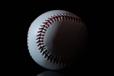 Siyah arka planı olan beyaz bir beyzbol topu.