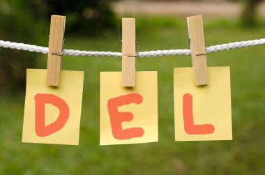 Turuncu harfli üç sarı yaprak DEL ve ahşap mandallar yeşil çimenlerin arka planına bağlı beyaz bir ipe bağlıdır.