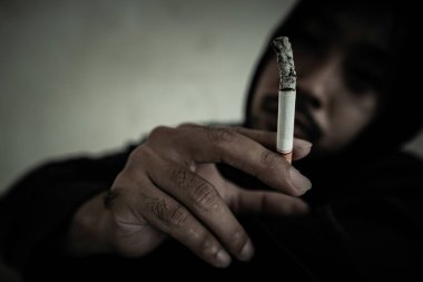 Depresyondaki Asyalı adam sigara içiyor. 