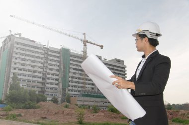 İnşaat alanının planlarını ve planlarını elinde tutan mühendis.