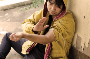 Bağımlı yerde oturuyor ve elinde şırıngayla uyuşturucu alıyormuş.