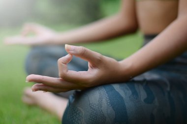 Parkta meditasyon yapan genç bir kadının kısmi görüntüsü