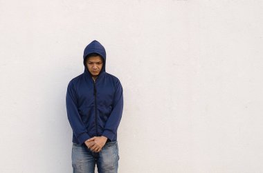 Yakışıklı, sıradan giysiler içinde, duvarın önünde duran üzgün bir adamın portresi.