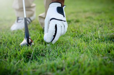 Golf sahasında golf sopasıyla golf topunu vuruyorum.