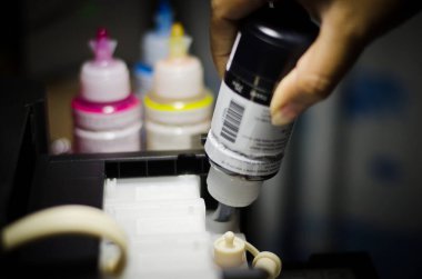 Yazıcıdaki beyaz plastik bir mürekkep tankına siyah mürekkep dökme sürecinin yakınlaştırılması 