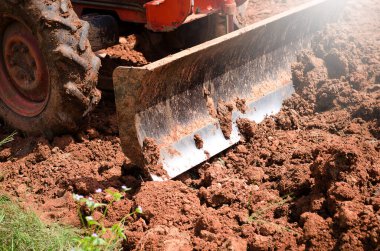 Yerde kepçeyle çalışan traktör.