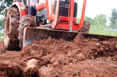 Yerde kepçeyle çalışan traktör.