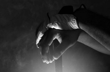 Çubuktaki golf eldiveni giymiş ellerin koyu renkli fotoğrafı. 