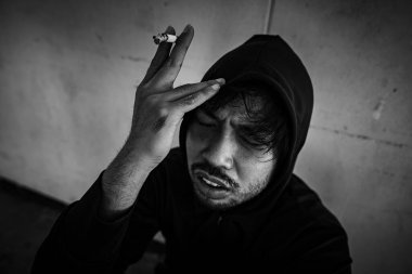 Depresyondaki Asyalı adam sigara içiyor. 