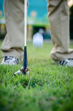 Golfçüler bir golf sopası tutuyor ve golf topu hareket ediyor.
