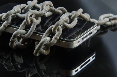 Zincirler koyu arkaplanı olan bir cep telefonuna sarılmıştı..