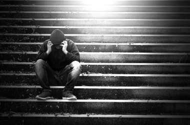 Üzgün depresif adam merdivenlerde oturuyor, siyah beyaz fotoğraf 