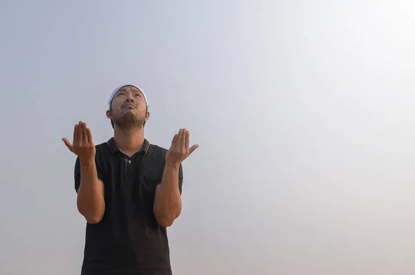 Müslüman genç adam dışarıda dua ediyor.