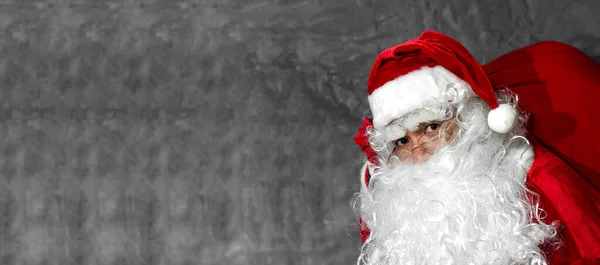 Kerstman Houdt Big Bag Zijn Schouders Grijze Achtergrond — Stockfoto