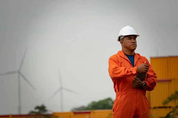 İnşaat alanının arka planında taslak olan üniformalı ve miğferli mühendis.