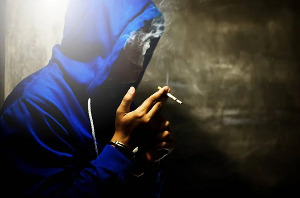 Foto Escura Com Homem Capuz Azul Fumando Perto Parede Luz — Fotografia de Stock