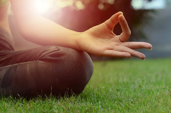 Parkta meditasyon yapan genç bir kadının kısmi görüntüsü