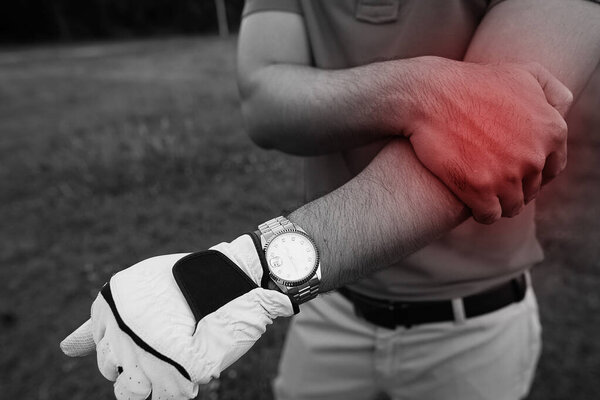 Golfer hand holding stick and another hand on the arm, arm hurts