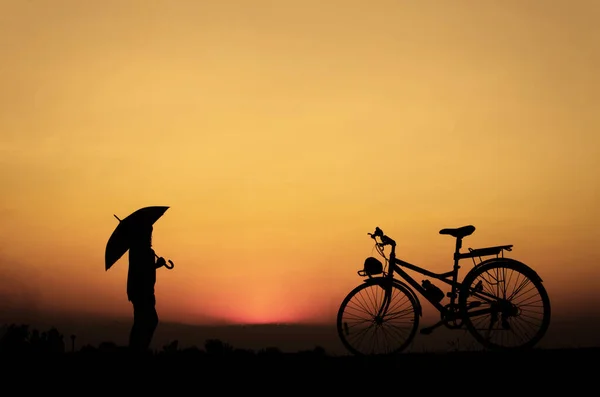 Silhouette Kezében Esernyő Kerékpározás Meleg Fényben — Stock Fotó