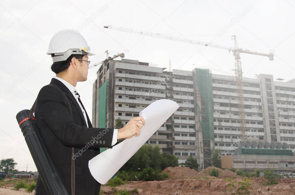 engineer holding blueprints and blueprint on the construction site