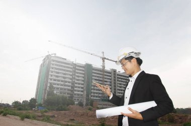 İnşaat alanının planları olan bir mimar.