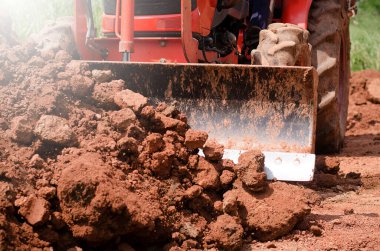 Yerde kepçeyle çalışan traktör.