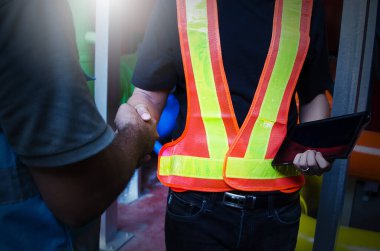 İki işçi fabrikada el sıkışıyor. 