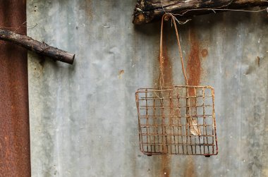 Eski, paslı ızgara ızgarası paslı ve paslı çizgileri olan metal bir duvara karşı eski bir ahşap üzerinde asılı.