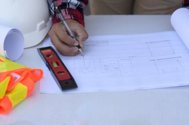 Planlarla çalışan bir mimarın üst görünümü 