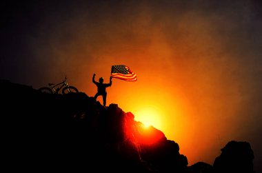 Dağın arka planında bayrak olan bisikletçi silueti 