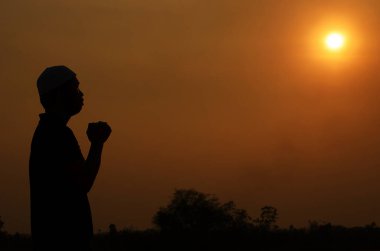 Müslüman genç adam dışarıda dua ediyor.