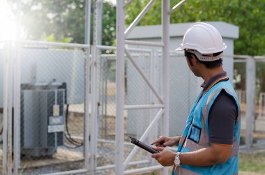 Tabletle çalışan sert şapkalı elektrikçi. 