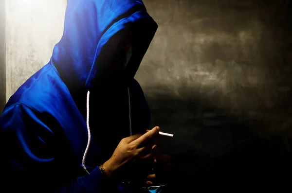 Foto Oscura Con Hombre Con Capucha Azul Fumando Cerca Pared — Foto de Stock
