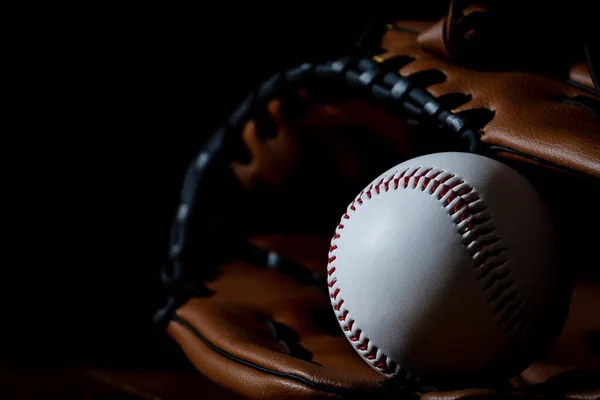 A white baseball ball and equipment with dark background