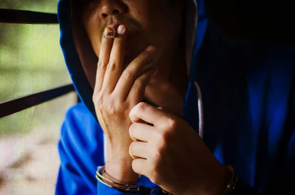 Темна Фотографія Чоловіком Наручниками Блакитній Шубці Курить Біля Стіни Язнений — стокове фото