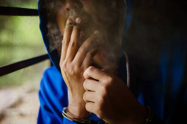 Foto Escura Com Homem Com Algemas Capuz Azul Fumando Perto — Fotografia de Stock