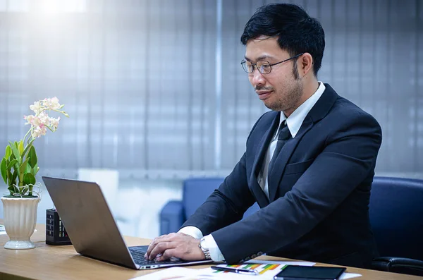 Uomo d'affari seduto con un computer portatile nel suo ufficio — Foto Stock