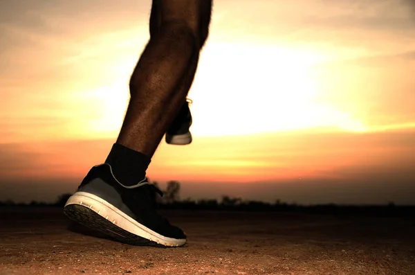 Close up on the leg of a runner with the sunset