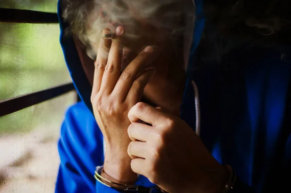 Foto Oscura Con Hombre Con Esposas Con Capucha Azul Fumando — Foto de Stock