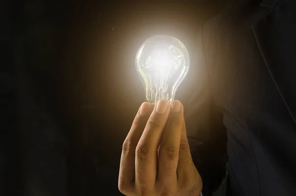 Businessman with illuminated light bulb balancing on his hand — Stock Photo, Image