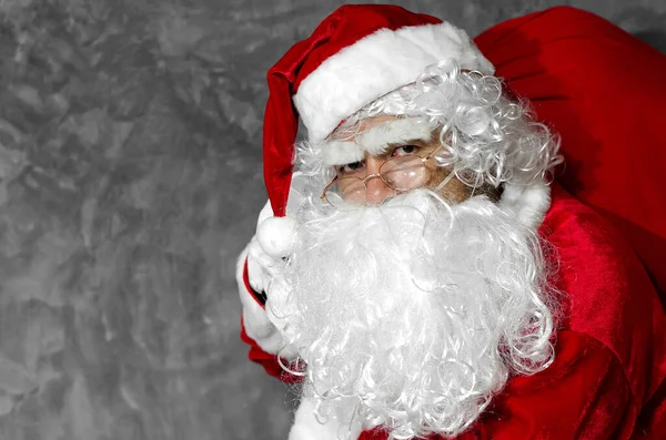 Der Weihnachtsmann Hält Grauen Hintergrund Die Große Tüte Den Schultern — Stockfoto