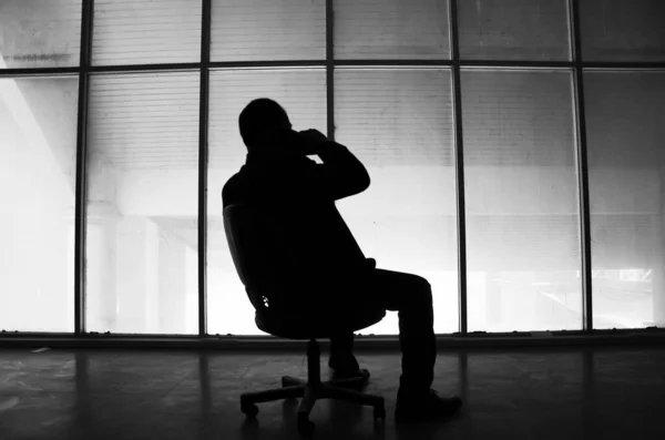 silhouette of a businessman in a chair in the office calling on the phone