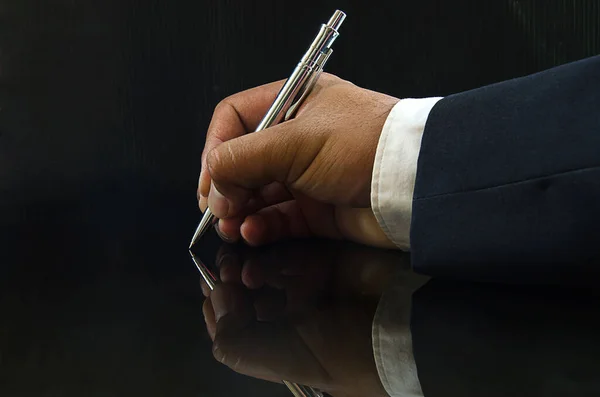 Επιχειρηματίας Χέρι Κρατώντας Ένα Στυλό Μέσα Σκοτεινό Φόντο — Φωτογραφία Αρχείου