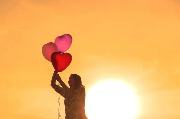 夕日に気球を持った女性のシルエットが ロイヤリティフリーのストック写真