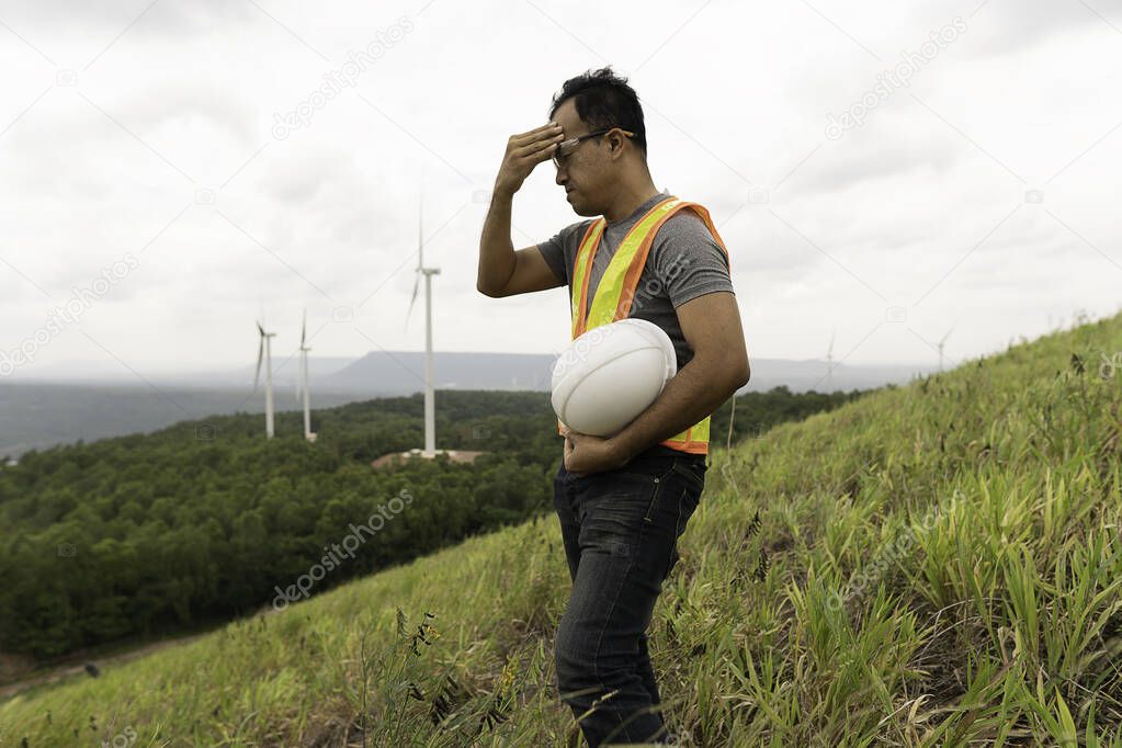 Electrical engineer man are standing stress with renewable power from wind turbines