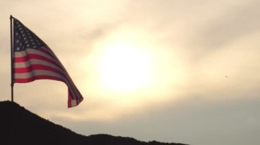 Gün batımında rüzgarda dalgalanan Amerikan bayrağının görüntüleri.