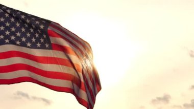 Gün batımında rüzgarda dalgalanan Amerikan bayrağının görüntüleri.