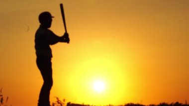 Eldivenli beyzbol oyuncusunun ve gün batımında beyzbol sopasının görüntüleri.