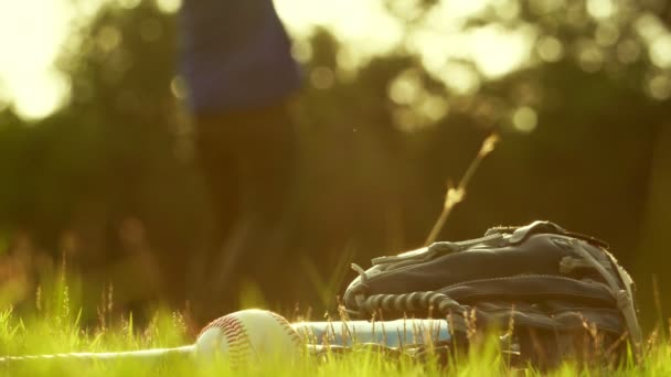 在温暖的光线下 球在地面上的特写镜头 背景中打棒球棍的运动员 — 图库视频影像
