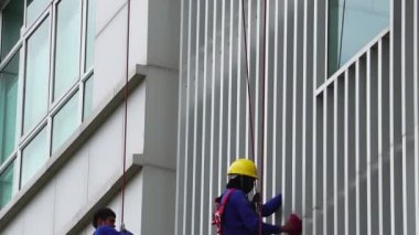 Yüksek ve yüksek katlı pencereleri temizleyen tanınmayan işçilerin görüntüleri